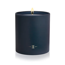 Load image into Gallery viewer, A navy blue matte candle in a matching cylindrical jar, lit with a small flame, featuring a gold Roman numeral II logo on the front, set against a clean white background.