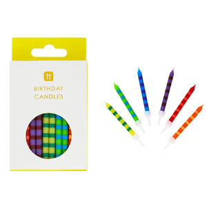 Box of striped rainbow birthday candles with seven individual candles fanned out, in red, orange, yellow, green, blue, and purple, colourful cake decorations with holders